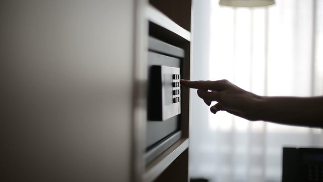 Female hands locking combination to safe in the hotel room