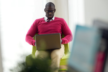Handsome young man working with his laptop at home.