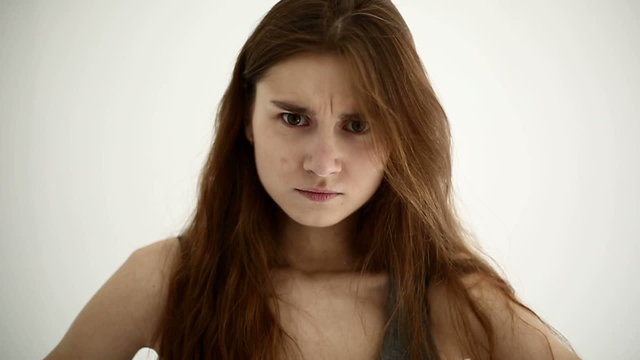 Young girl makes an angry face at white background