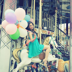 Merry-go-round young woman playing on carousel, toned.