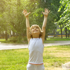 Obraz premium Little boy has fun in the summer rain, toned