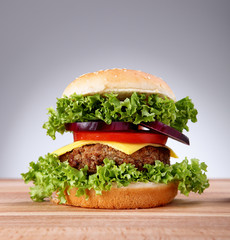Hamburger with grilled meat and cheese on a wooden surface 

