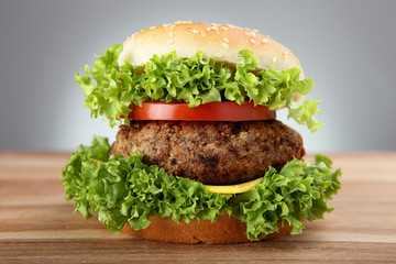 Hamburger with grilled meat and cheese on a wooden surface 

