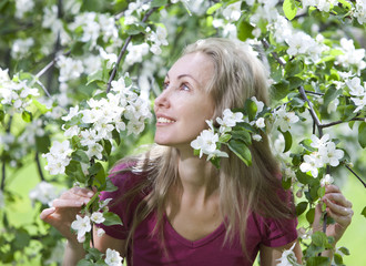 young attractive woman standing near blossoming apple tree...