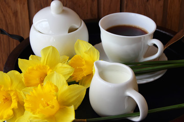 Cup of coffee, milk and daffodils.