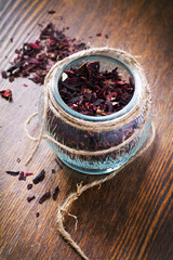 Heap of dried hibiscus calyces in a jar on a wooden table