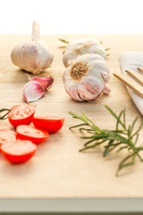 Fresh tomatoes, garlic and rosemary on the kitchen table.