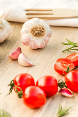 Fresh tomatoes, garlic and rosemary on the kitchen table.