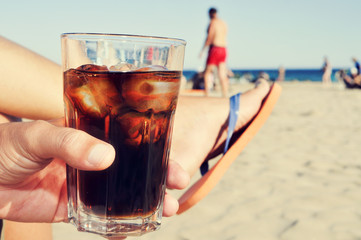 young man hanging out on the beach with a cola drink