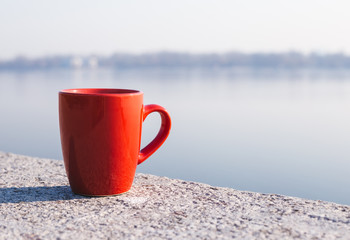 Red coffee cup on the seafront in the morning