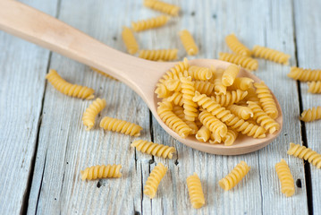 Uncooked fusilli pasta on old wooden table