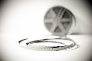 Super 8 mm filmstrip with reel in background black and white