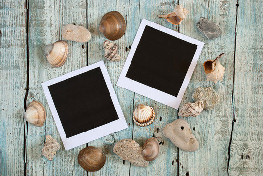 Sea shells and instant photo frames on old wooden table