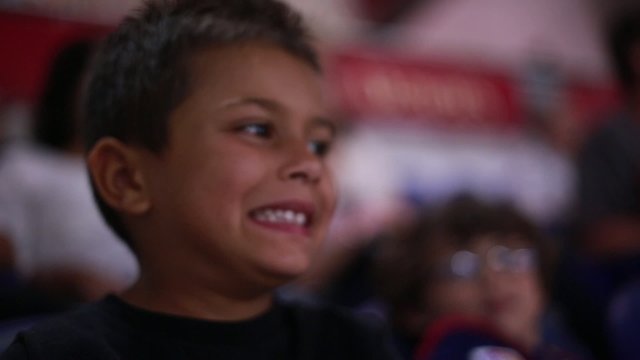 Cute kid watching and enjoying a game from stands