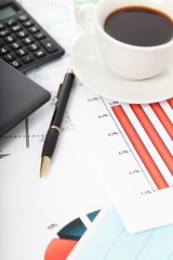 Calculator and cup of coffee on the financial documents