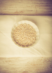 Barley groats in bowl on a white wood. Vintage photo