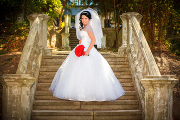 Beautiful bride sits on the stairs of the old church