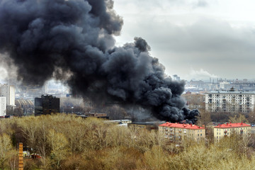 Fototapeta na wymiar Column of black smoke rising above fireplace in the city