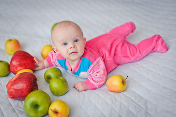 Fototapeta na wymiar Cute baby surrounded by bright beautiful large fresh apples
