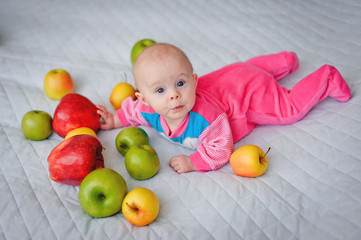 Fototapeta na wymiar Cute baby surrounded by bright beautiful large fresh apples