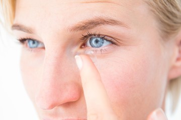 Naklejka premium Pretty blonde applying contact lens