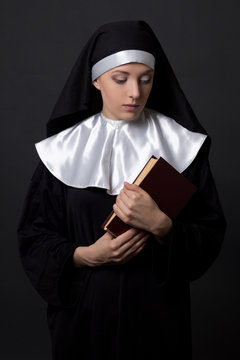 Young Woman In Nun Veil With Book Over Grey