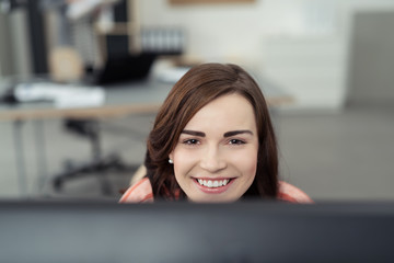 junge frau schaut lächelnd über den computer-bildschirm