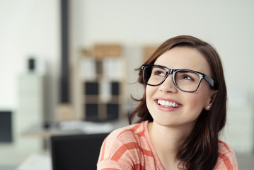 zufriedene junge frau im büro schaut lächelnd nach oben - obrazy, fototapety, plakaty