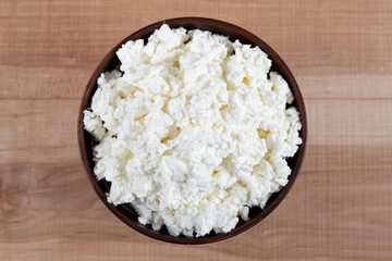 Fresh cottage cheese in a bowl on a wooden table.