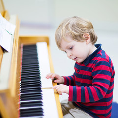 Two years old toddler boy playing piano, music schoool.