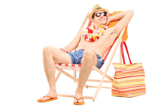 Relaxed man sitting shirtless in a sun lounger