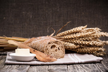 Tasty bread with wheat on wooden background.