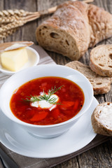 Tasty soup with bread on a wooden background.