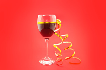 Wine in glasses with golden ribbon on red background.