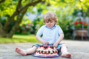 Little boy celebrating his birthday in home's garden with big ca