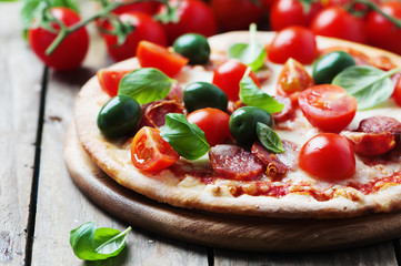 Italian hot pizza with salami, olive and tomato