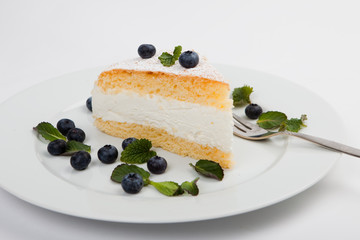 Käsekuchen mit Minze und Heidelbeeren, weißer Hintergrund