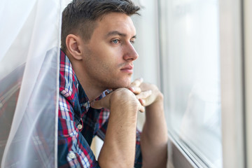 Fototapeta na wymiar Handsome pensive man guy watching through the window concept