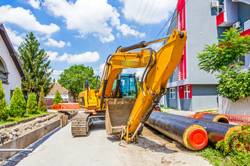 Yellow excavator at construction site in urban settlement