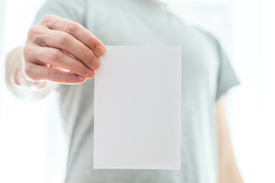 Man In A Grey T-shirt Holding A Blank White Piece Of Paper