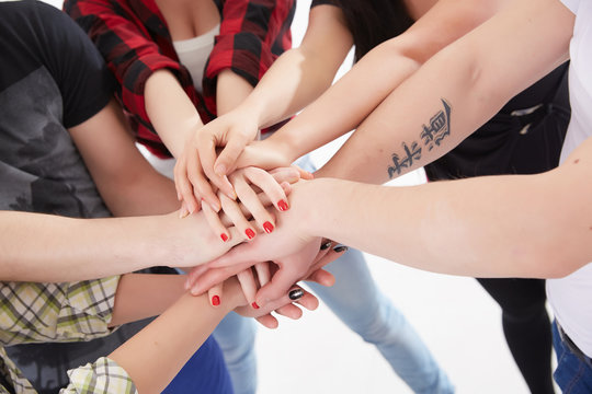 group of students in a circle of hands stacked together © photoniko