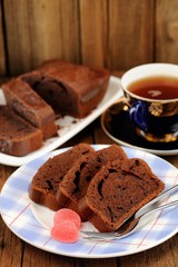 Homemade chocolate cake cut with pink candies and tea in blue cu