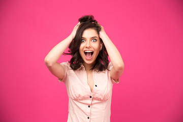 Amazed young woman shouting over pink background