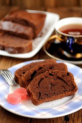 Homemade chocolate cake cut with pink candies and tea in blue cu