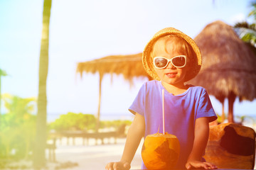 Obraz na płótnie Canvas little boy drinking coconut cocktail on the beach