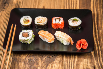 Sushi pieces collection with bamboo chopsticks, isolated on wooden table