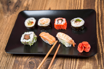Sushi pieces collection with bamboo chopsticks, isolated on wooden table
