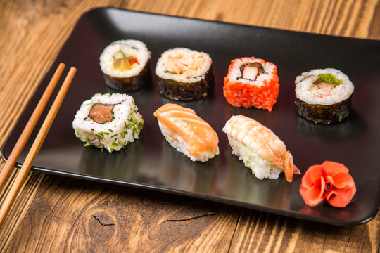 Sushi pieces collection with bamboo chopsticks, isolated on wooden table