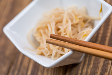 Fresh platter of bean sprouts with chopsticks on wooden table