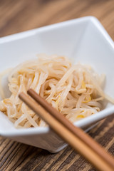 Fresh platter of bean sprouts with chopsticks on wooden table